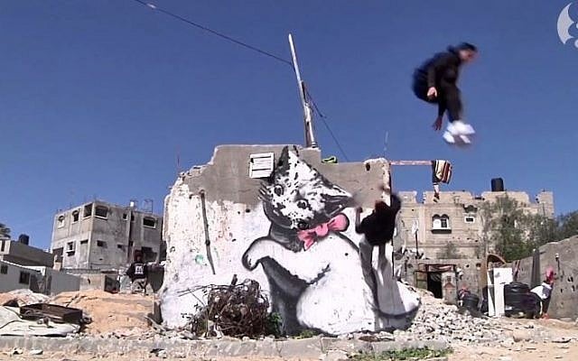 Gaza city parkour enthusiasts perform in front of graffiti by British artist Banksy in Gaza City. (screen capture: Youtube/The Guardian) Gaza city parkour enthusiasts perform in front of graffiti by British artist Banksy in Gaza City. (screen capture: Youtube/The Guardian)
