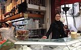 Shahar Levi sings amid Basher's cheeses in the shuk, at a promo for the June opera festival in Jerusalem (photo credit: Jessica Steinberg/Times of Israel)