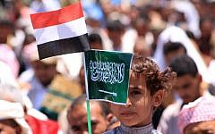A Yemeni child holds Saudi (R) and Yemeni national flags during a demonstration in the strategic city of Taez on March 27, 2015, in support of the Saudi-led operation against Shiite rebels in the country (photo credit: AFP/STR)