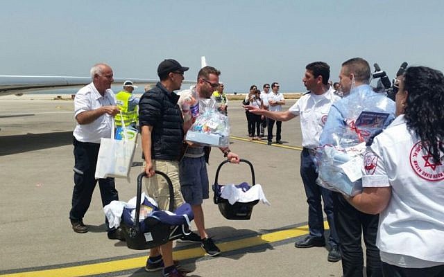 Interior Minister Gilad Erdan (2nd R) and Director of Magen David Adom Eli Bean (3rd R) greet parents carrying their newborn babies as they arrive in Israel, April 27, 2015. (MDA) Interior Minister Gilad Erdan (2nd R) and Director of Magen David Adom Eli Bean (3rd R) greet parents carrying their newborn babies as they arrive in Israel, April 27, 2015. (MDA)