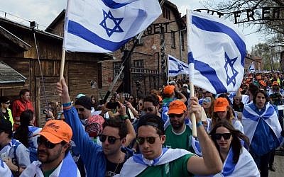 Participants wave Israeli flags at the main gate of the former Nazi German Auschwitz-Birkenau death camp during the 'March of the Living' at in Oswiecim, Poland on April 16, 2015. (Photo credit: Janek Skarzynski/AFP)