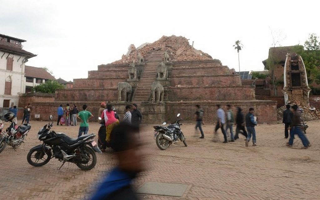 People walk through the ruins of Bhaktapur's Durbar Square, a UNESCO World Heritage Site, on the outskirts of Kathmandu, on April 27, 2015, two days after a 7.8 magnitude earthquake hit Nepal. (Photo credit: Prakash Mathema/AFP)