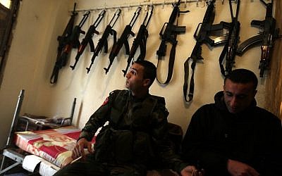 Palestinian militants sit at their post in the refugee camp of Ain Al-Helweh, near the southern Lebanese city of Sidon, on March 16, 2015. (photo credit: AFP / JOSEPH EID)