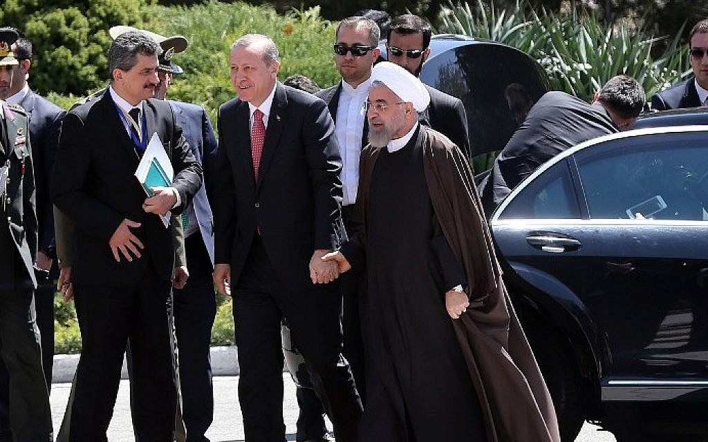 Iran's President Hassan Rouhani (R) holds hands with Turkish President Recep Tayyip Erdogan (C) as they walk during an official welcoming ceremony following the latter's arrival at the Saadabad Palace in Tehran on April 7, 2015 (Photo credit: Atta Kenare/AFP)