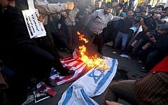Iranians burn and stomp on Israeli and American flags during a demonstration against the Saudi-led coalition’s Operation Decisive Storm against the Houthi rebels in Yemen, outside the Saudi Embassy in Tehran, April 13, 2015. (AFP/Atta Kenare)