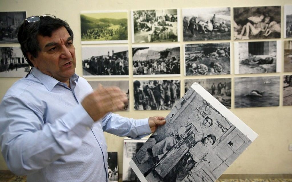 Armenian Serop Sahagian, the head of the Homenetmen Club, hang pictures to be displayed in an exhibition marking the 100th anniversary of the mass killings of Armenians under the Ottoman Empire in 1915, on April 17, 2015 in the Armenian Quarter in Jerusalem's Old City. Armenians around the world will mark on April 24, 2015 the centenary of the World War I-era mass killings of their kin by Ottoman Turks in what they insist was a genocide -- a term fiercely rejected by Turkey. (photo credit: AFP PHOTO / GALI TIBBON)