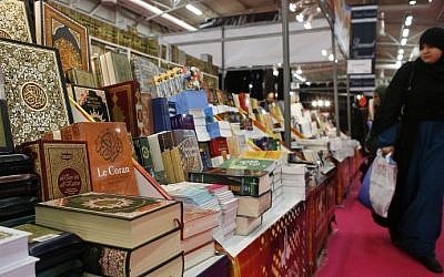 A woman walking past a stands displaying the Muslim Quran and other literature during the 32nd Annual Meeting of France's Muslims, at Le Bourget Exhibition center, north of Paris, April 3, 2015 (Photo credit: Thomas Samson/AFP)