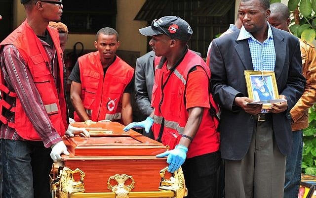 A relative holds a portrait of his relative as he watches her coffin being rolled out by Kenya Red Cross personnel at Chiromo funeral parlor in Nairobi, April 9, 2015. (photo credit: AFP/STRINGER)