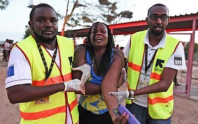 Paramedics help a student who was injured during an attack by Somalia's al-Qaeda-linked al-Shabab gunmen on the Garissa University campus in Garissa on April 2, 2015. (photo credit: AFP/ Carl Dd Souza)