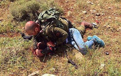An Israeli soldier pins down a Palestinian man who stabbed another soldier near the West Bank security fence, April 2, 2015 (photo credit: IDF spokesperson)