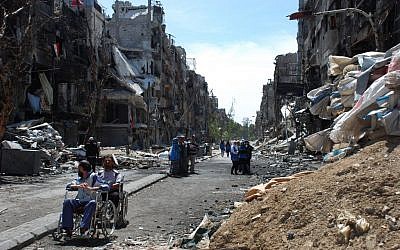 In this picture provided by the United Nations Relief and Works Agency for Palestine Refugees in the Near East, two men on their wheelchairs wait to receive food supplies at a damaged street in the besieged Yarmouk refugee camp, on the southern edge of the Syrian capital Damascus, Syria, Thursday, April 24, 2014. (AP)