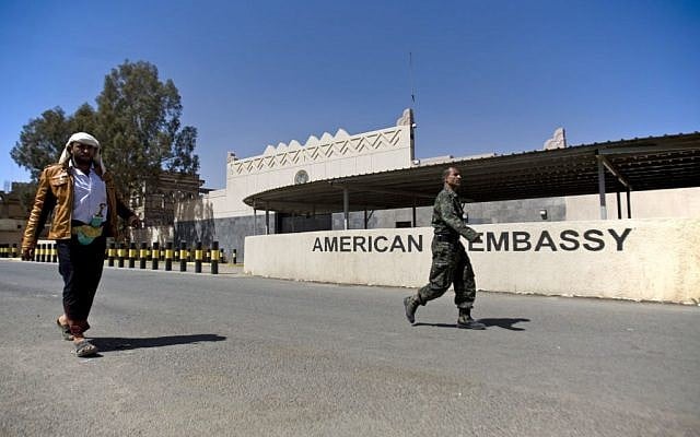 Houthi Yemenis walk past the gate of the main entrance of the closed U.S. embassy after Yemeni police opened the road in front of it, in Sanaa, Yemen, Wednesday, March 4, 2015 (photo credit: AP/Hani Mohammed)
