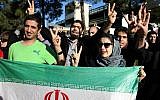 Iranians flash the Victory sign as they hold their country's flag while waiting for the arrival of Foreign Minister Mohammad Javad Zarif from Lausanne, Switzerland, at the Mehrabad airport in Tehran, Iran, on April 3, 2015. (AP/Ebrahim Noroozi)