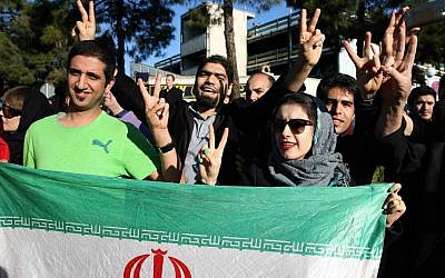 Iranians flash the Victory sign as they hold their country's flag while waiting for the arrival of Foreign Minister Mohammad Javad Zarif from Lausanne, Switzerland, at the Mehrabad airport in Tehran, Iran, on April 3, 2015. (AP/Ebrahim Noroozi)