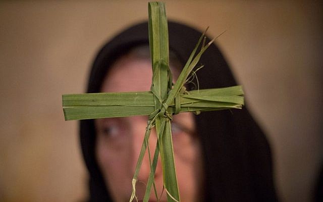 A Greek Orthodox woman holds a palm fond in the Church of the Holy Sepulcher, traditionally believed by many to be the site of the crucifixion and burial of Jesus Christ, during Orthodox Palm Sunday, in Jerusalem, Sunday, April 5, 2015. (photo credit: AP/Ariel Schalit)