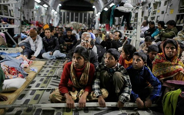 Survivors of Saturday's earthquake hold on to a cable as a military takes off with evacuees from Kathmandu to New Delhi during a midnight rescue mission by Indian Air Force, in Kathmandu, Nepal, Wednesday, April 29, 2015. (AP Photo/Altaf Qadri)