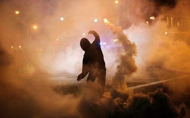 A protester throws a tear gas canister back toward riot police after a 10 p.m. curfew went into effect in the wake of Monday's riots following the funeral for Freddie Gray, Tuesday, April 28, 2015, in Baltimore. (AP Photo/David Goldman)
