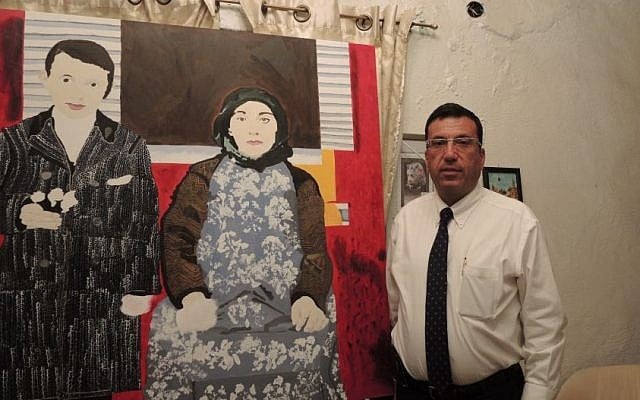 Kevork Nalbandian, a lawyer and social worker who is on the planning committee for the 100th anniversary in Jerusalem, stands in his home next to a painting made by a 17-year-old local Armenian teenager dealing with themes of memory and Armenian identity.  (Melanie Lidman/Times of Israel)