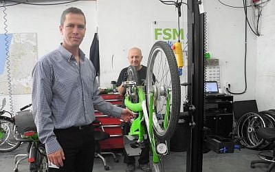 Ofer Sela, the CEO of FSM, a conglomeration of companies that operates Tel-O-Fun, with a bike mechanic in the Tel-O-Fun headquarters in south Tel Aviv. (photo credit: Melanie Lidman/Times of Israel)