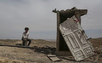 A young Palestinian girl sits near an outhouse in the Palestinian village of Al Mufakara, off Route 60, in South Hebron Mountain, in the West Bank, on April 23, 2014. This area had been declared by Israel as a closed military zone, making any housing there illegal. As a result, most inhabitants here live in caves for fear of home demolitions (photo credit: Hadas Parush/Flash90)