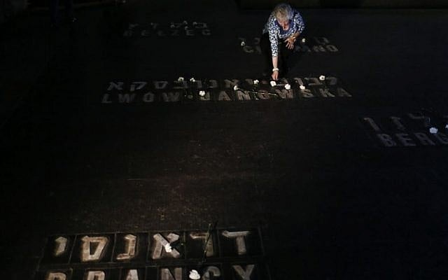 Relatives and friends of Holocaust survivors place flowers and candles on names of concentration camps seen on the floor of the Hall of Remembrance at Yad Vashem, on Holocaust Remembrance Day, April 28, 2014. Photo credit: Miriam Alster/Flash90)
