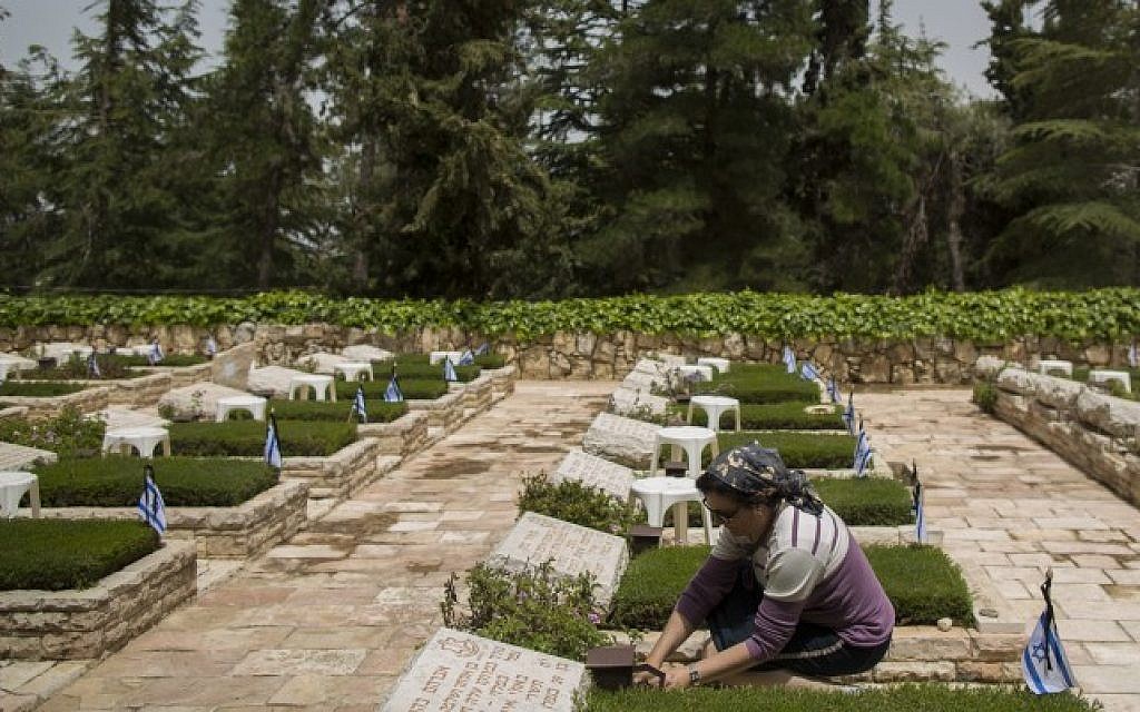 An Israeli woman lights a candle at a grave in Mount Herzl Military Cemetery in Jerusalem on April 20, 2015 (Photo credit: Yonatan Sindel/Flash90)