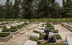 An Israeli woman lights a candle at a grave in Mount Herzl Military Cemetery in Jerusalem on April 20, 2015 (Photo credit: Yonatan Sindel/Flash90)