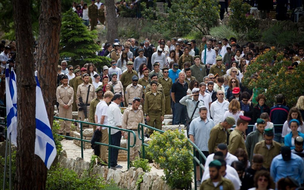 Israelis stand next to graves of Israeli soldiers at the Mt. Herzl military cemetery in Jerusalem, as a two-minute siren sounded across Israel, marking Memorial Day on April 22, 2015. (photo credit: Miriam Alster/Flash90)