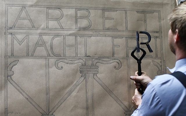 Construction plans hang in a workshop of blacksmith Michael Poitner as he works on a replica of the Dachau Nazi concentration camp gate with the writing "Arbeit macht frei" (Work Sets you Free) in Biberbach near Dachau, Germany, Thursday, April 16, 2015. (Photo credit: AP/Matthias Schrader) Construction plans hang in a workshop of blacksmith Michael Poitner as he works on a replica of the Dachau Nazi concentration camp gate with the writing "Arbeit macht frei" (Work Sets you Free) in Biberbach near Dachau, Germany, Thursday, April 16, 2015. (Photo credit: AP/Matthias Schrader)