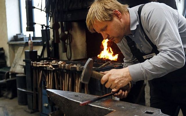 Blacksmith Michael Poitner works on a replica of the Dachau Nazi concentration camp gate with the writing "Arbeit macht frei" (Work Sets you Free) in Biberbach near Dachau, Germany, Thursday, April 16, 2015. The original gate was stolen in November 2014. (Photo credit: AP/Matthias Schrader) Blacksmith Michael Poitner works on a replica of the Dachau Nazi concentration camp gate with the writing "Arbeit macht frei" (Work Sets you Free) in Biberbach near Dachau, Germany, Thursday, April 16, 2015. The original gate was stolen in November 2014. (Photo credit: AP/Matthias Schrader)