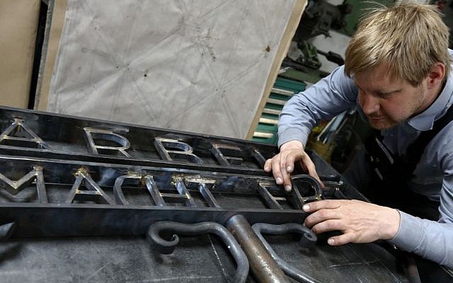 Blacksmith Michael Poitner works on a replica of the Dachau Nazi concentration camp gate with the writing "Arbeit macht frei" (Work Sets you Free) in Biberbach near Dachau, Germany, Thursday, April 16, 2015. The original gate was stolen in November 2014. (Photo credit: AP/Matthias Schrader) Blacksmith Michael Poitner works on a replica of the Dachau Nazi concentration camp gate with the writing "Arbeit macht frei" (Work Sets you Free) in Biberbach near Dachau, Germany, Thursday, April 16, 2015. The original gate was stolen in November 2014. (Photo credit: AP/Matthias Schrader)
