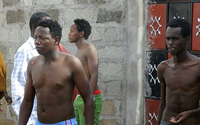 Some students without their shirts of the Garissa University College get out of a house where they seek refuge after escaping from an attack by gunmen in Garissa, Kenya, Thursday, April 2, 2015. (photo credit: AP Photo)