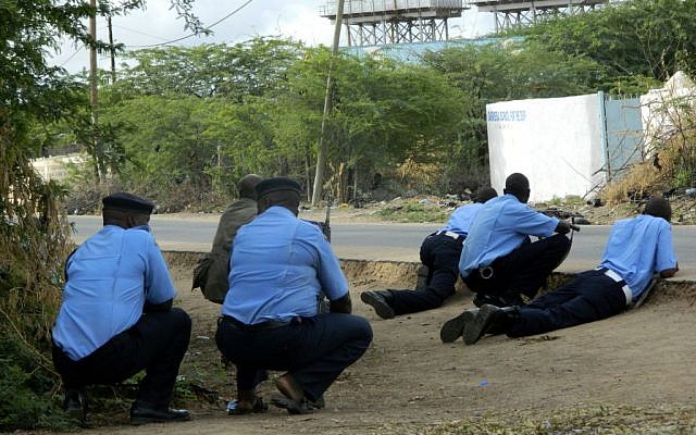 Kenyan police officers take cover outside the Garissa University College during an attack by gunmen in Garissa, Kenya, Thursday, April 2, 2015.  (photo credit: AP)