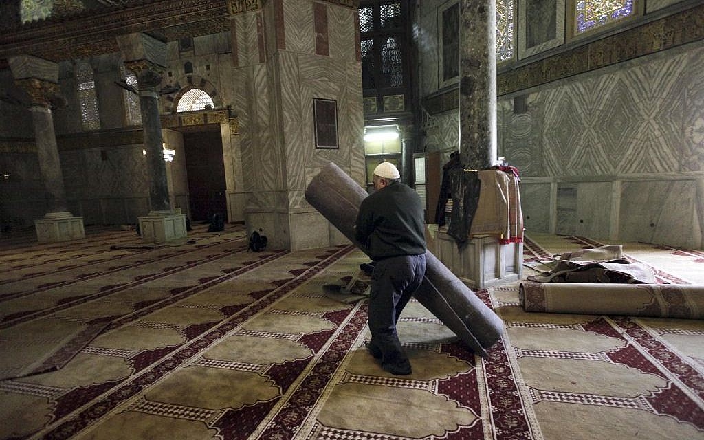 In this Sunday, April 19, 2015 photo, a worker carries new carpets at the Dome of the Rock shrine in Jerusalem. The Dome of the Rock enshrines the large rock slab where Muslim tradition says Mohammed ascended to heaven. Jews believe the rock may be where the holiest part of the two ancient temples stood about 2,000 years ago. (photo credit: AP/Mahmoud Illean)