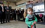 A girl holds a snack at a school, during the visit of Pierre Krahenbuhl, commissioner-general of the United Nations Relief and Works Agency (UNRWA), background left, in Yarmouk refugee camp in Damascus, Syria, Sunday, April 12, 2015. (AP Photo)