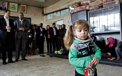 A girl holds a snack at a school, during the visit of Pierre Krahenbuhl, commissioner-general of the United Nations Relief and Works Agency (UNRWA), background left, in Yarmouk refugee camp in Damascus, Syria, Sunday, April 12, 2015. (AP Photo)
