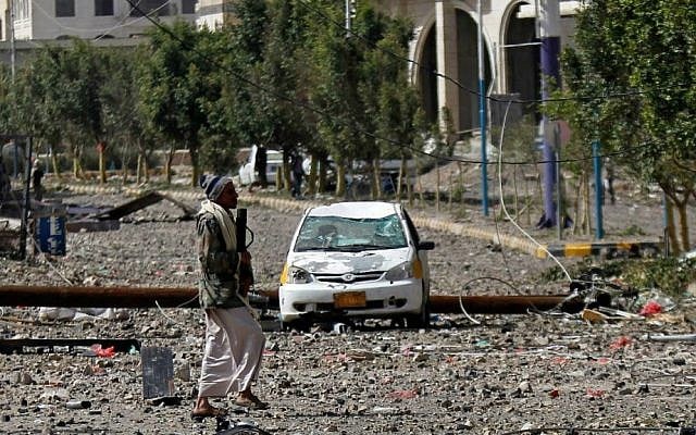 A Shiite fighter known as a Houthi walks on a street littered by debris after a Saudi-led airstrike hit a site where many believe the largest weapons cache in Yemen's capital, Sanaa, is located on Monday, April 20, 2015. (AP Photo/Hani Mohammed)