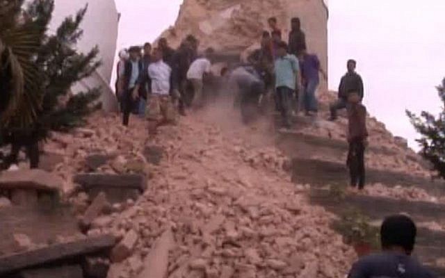 In this image from AP video people search in a buildings rubble in Kathmandu, Nepal after a strong earthquake hit the area Saturday April 25, 2015. (Photo credit: AP video via AP)