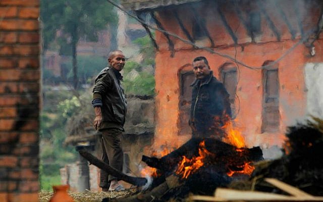 Nepalese people stand beside the funeral pyre of a family member who died in Saturday's earthquake in Bhaktapur, Nepal, Sunday, April 26, 2015. (AP Photo/Niranjan Shrestha)