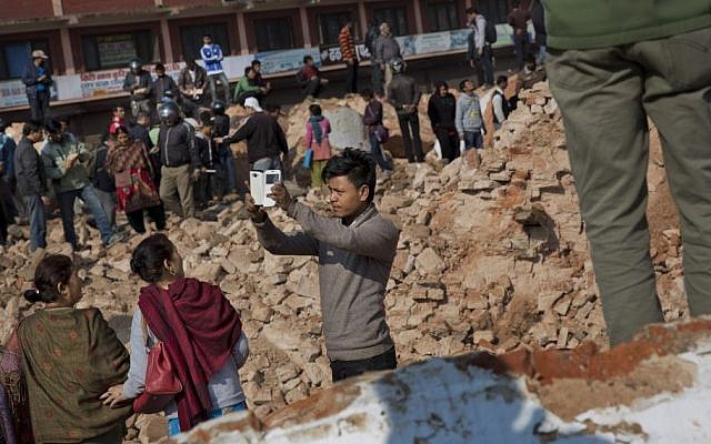 A man takes a selfie at the historic Dharahara Tower, a city landmark, that was damaged in Saturday’s earthquake in Kathmandu, Nepal, Monday, April 27, 2015. (photo credit: AP/Bernat Armangue) 