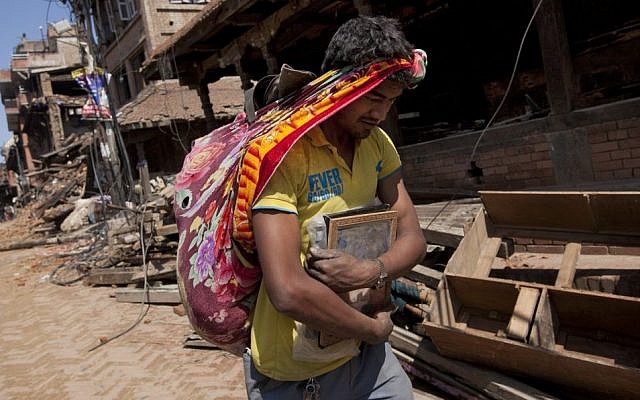 A Nepalese man carries his belongings from earthquake debris in Bhaktapur, on the outskirts of Kathmandu, Nepal, Monday, April 27, 2015. (photo credit: AP/Niranjan Shrestha)