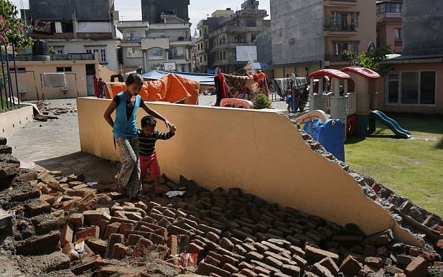 A young girl walks with a boy over a collapsed school playground in Kathmandu, Nepal, Monday, April 27, 2015. (photo credit: AP /Wally Santana) A young girl walks with a boy over a collapsed school playground in Kathmandu, Nepal, Monday, April 27, 2015. (photo credit: AP /Wally Santana)