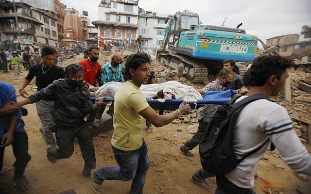 Volunteers carry the body of a victim on a stretcher, recovered from the debris of a building that collapsed after an earthquake in Kathmandu, Nepal, Saturday, April 25, 2015. (photo credit: AP Photo/ Niranjan Shrestha)