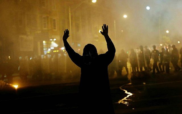 A protester walks away as police in riot gear advance on the crowd after a 10 p.m. curfew went into effect in the wake of Monday's riots following the funeral for Freddie Gray, Tuesday, April 28, 2015, in Baltimore. (AP Photo/David Goldman)