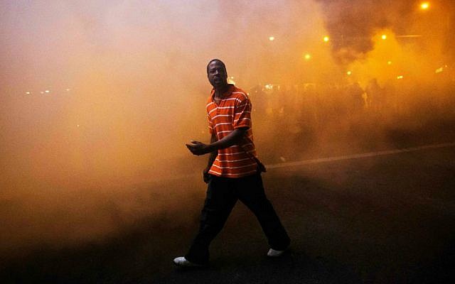 A protester walks through a cloud of tear gas as police in riot gear advance on the crowd after a 10 p.m. curfew went into effect in the wake of Monday's riots following the funeral for Freddie Gray, Tuesday, April 28, 2015, in Baltimore. (AP Photo/David Goldman)