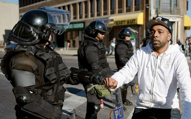 A man on a bicycle greets Maryland State Troopers Tuesday, April 28, 2015, in the aftermath of rioting following Monday's funeral for Freddie Gray, who died in police custody. (AP Photo/Matt Rourke)