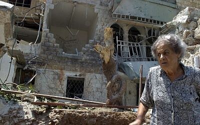 An Israeli woman walks in front of a building destroyed by a Katyusha rocket in the town of Haifa on August Monday 07.2006. (photo credit: Max Yelinson /Flash90)