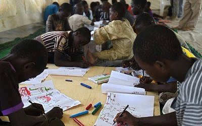 Young Nigerian refugees draw on April 6, 2015 during a therapy program managed by UNICEF in a refugee camp near Baga Sola (photo creidt: AFP /PHILIPPE DESMAZES)