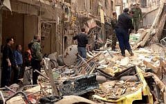 Syrians walk through the rubble following reported rocket attacks by rebel fighters on the Christian neighborhood of Suleimaniyah in northern Aleppo. (photo credit: AFP/George Ourfalian)