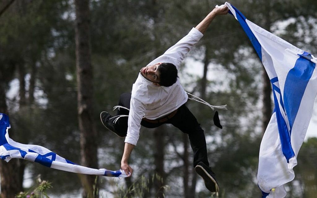 Ultra-Orthodox Jewish Mickey Hayat practices Capoeira, a Brazilian martial art, as he holds an Israeli national flag, ahead of Israeli Independence Day, on April 17, 2015. (Nati Shohat/Flash 90)